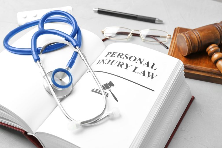 personal injury book open on a desk with a stethoscope on top. Near the book is a gavel, glasses, and a pen.