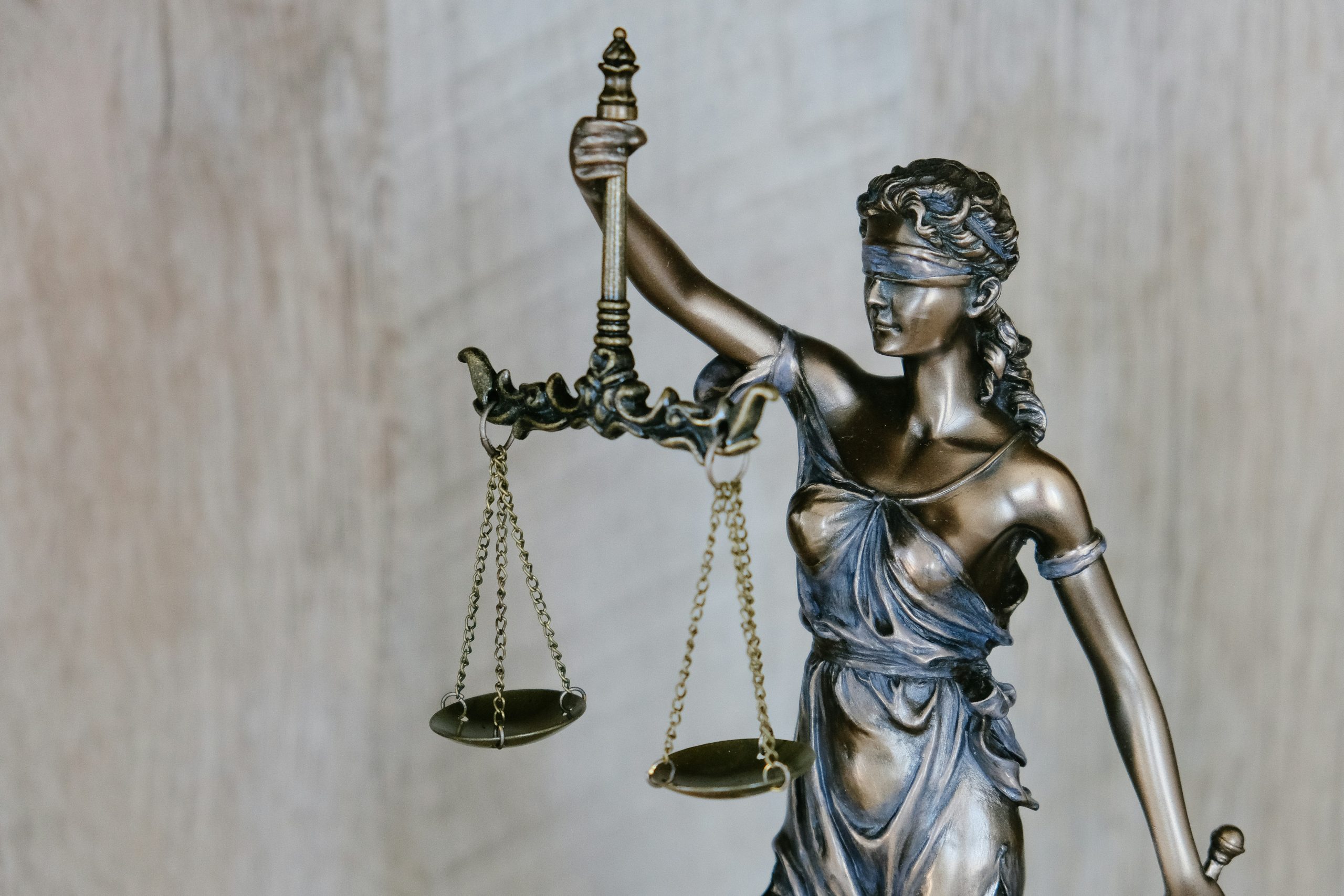 A metal statue of Lady Justice who is blindfolded and holding scales. Photo by Tingey Injury Law Firm on Unsplash